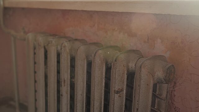 Close up of cast iron radiator inside Soviet era apartment lit by soft daylight