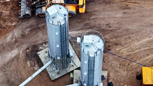 Aerial view of industrial cement silos at a construction site with heavy machinery