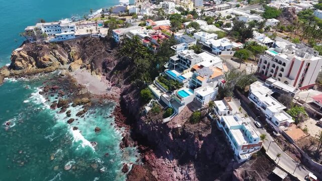 A sophisticated aerial tracking shot following the luxury cliffside residential architecture along Mazatl&aacute;n's historic Paseo del Centenario.