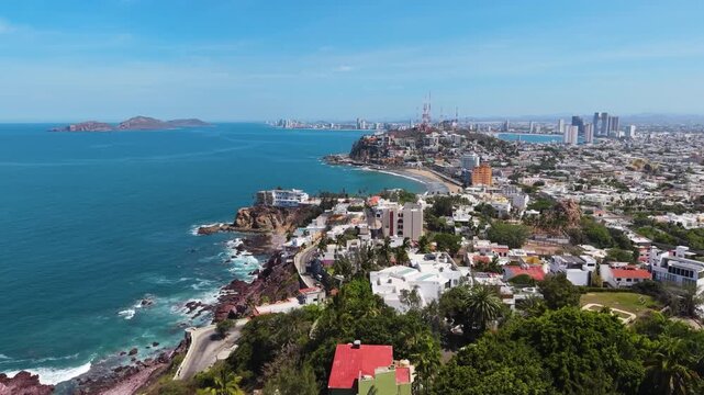 A sweeping wide-angle aerial shot capturing the dramatic Mazatl&aacute;n coastline with the historic El Faro lighthouse atop the peninsula.