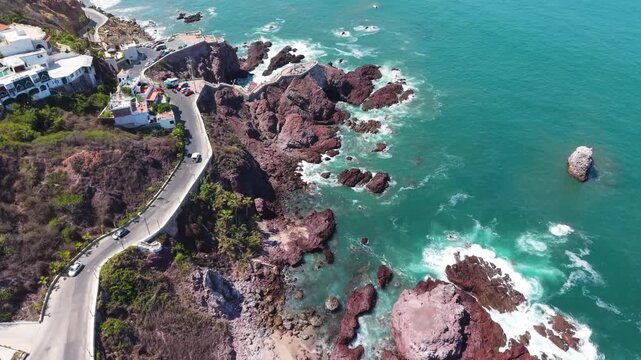 A dynamic aerial shot tracking the winding coastal road as it hugs Mazatl&aacute;n&rsquo;s rugged, volcanic-influenced shoreline.