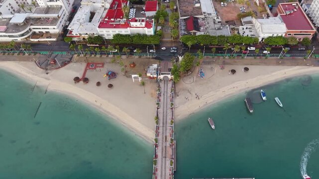 A striking top-down drone perspective showcasing the linear architecture of the Malec&oacute;n pier extending into the turquoise waters of La Paz.