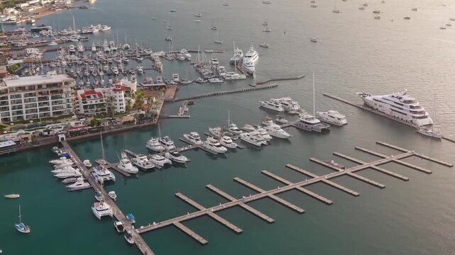 A smooth, high-angle aerial slide showcasing an array of luxury yachts and catamarans anchored within the La Paz harbor.