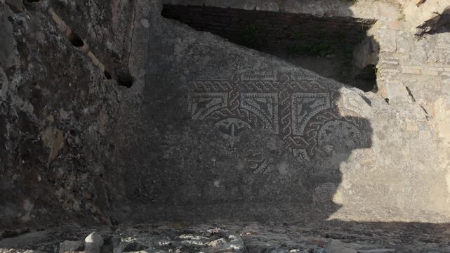 Ground-level view of an ancient Roman mosaic floor preserved at the Volubilis archaeological site in Morocco, showcasing geometric patterns within their original architectural setting.