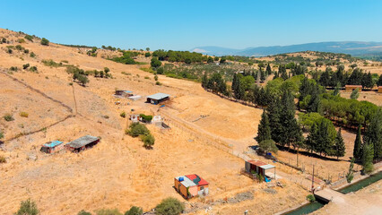 Bergama, Turkey. Aerial view of arid hills with sparse vegetation, dry grassy slopes and rural dirt tracks on windy hot afternoon.. Aerial View © Video Render