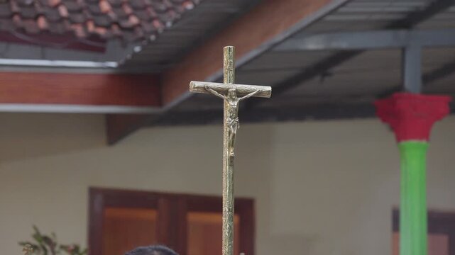 Golden metal processional crucifix cross with Jesus Christ figure outdoors