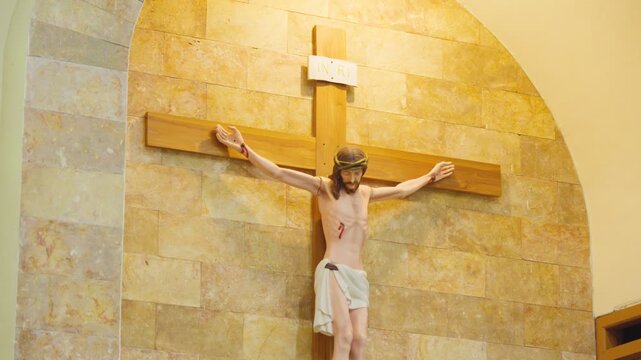 Jesus Christ crucifix sculpture on natural stone wall inside a catholic church