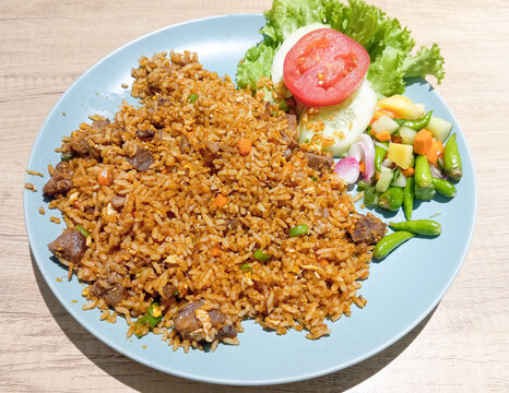 Acehnese Fried Rice with Sliced Beef Served with Fresh Vegetables on a Blue Plate