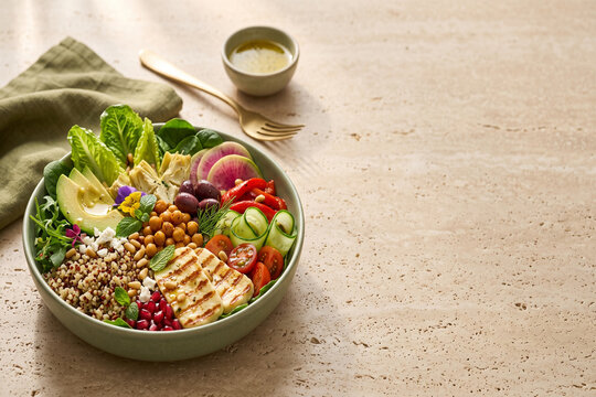 Mediterranean quinoa salad bowl with grilled halloumi chickpeas avocado olives and fresh vegetables top view with copy space