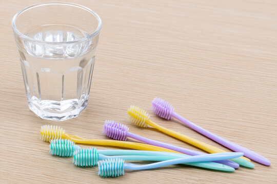 Interdental brush dental care oral hygiene tooth cleaning glass water wood surface pastel color minimalist copy space clean bright morning light soft shadow top view hygiene tool dental tool small