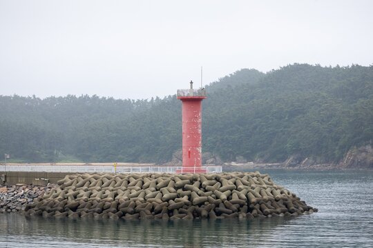 Lighthouse on a breakwater with mountains and the sea