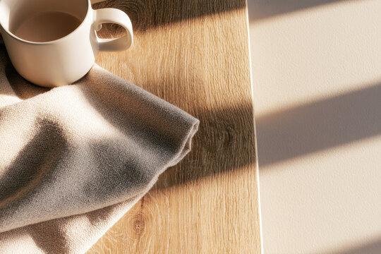 Warm sunlight wooden table mug fabric wrap cozy morning light natural shadow