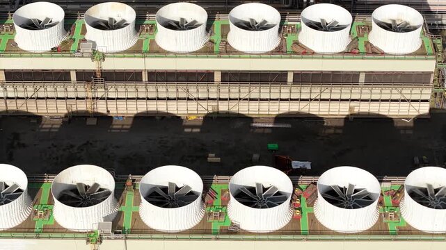 Drone close-up of industrial cooling fans spinning in rows at a combined heat and power plant in Immingham, UK.
