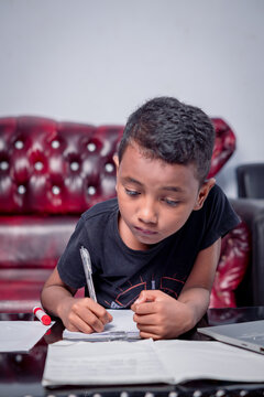 Asian boy focuses on studying using laptop in living room of house
