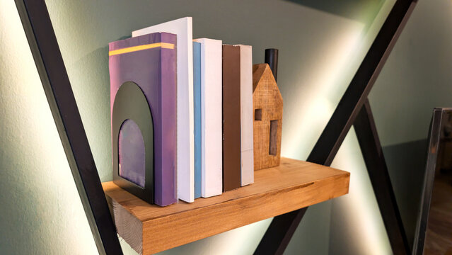 Modern Wooden Floating Shelf with Colorful Books, Metal Bookend, and Cozy Ambient Backlight in Home Interior