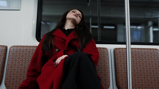A beautiful brunette in an alizarin red coat riding the metro, urban street fashion
