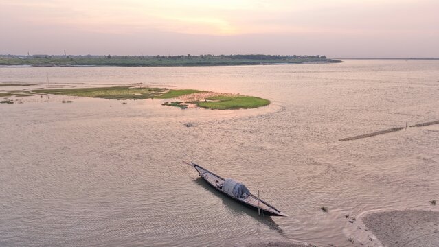 Traditional Wooden Boat on a River Near a Green Sandbar in Bangladesh