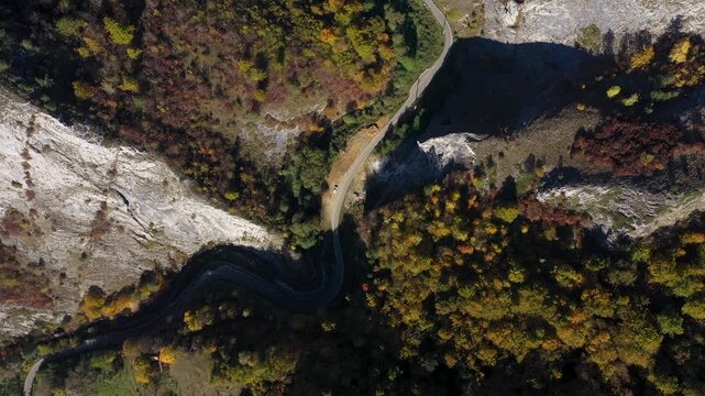  Aerial top down view of deep canyon, gorge road in autumn forest 