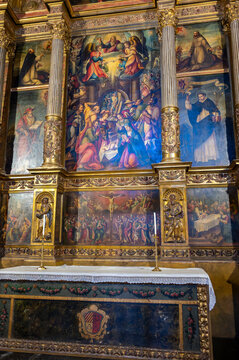 Vertical view of a ornate renaissance altarpiece (retablo) featuring painted panel scenes of religious figures and central biblical narrative, framed by gilded classical columns, positioned above a cl