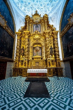 Grand baroque gilded main retable inside a side chapel featuring geometric tiled flooring and ornate dome at the Cathedral of San Salvador, La Seo in Zaragoza, Spain.