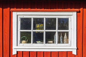 Window of an old red barn with glass bottles and a coffee pot © Lars Johansson
