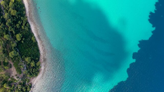 Aerial view of turquoise sea water and forested coastline