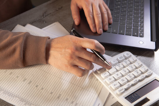 Businessman working with laptop and calculator in office. Close up.