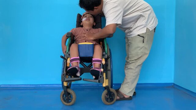 Father caring for child living with Cerebral Palsy in wheelchair wearing AFO brace