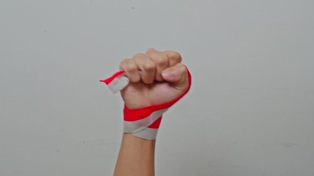 Raised clenched fist wrapped with red and white ribbon for Indonesian independence day