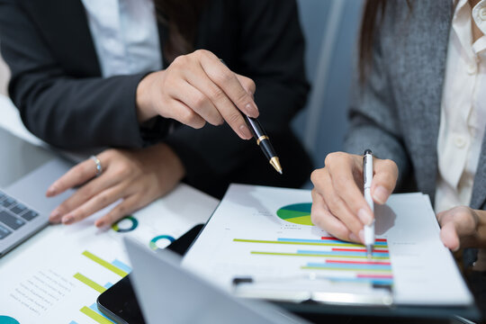  Two professional women work together at a desk, reviewing information on a laptop, collaborating on teamwork and business planning, and analyzing data.