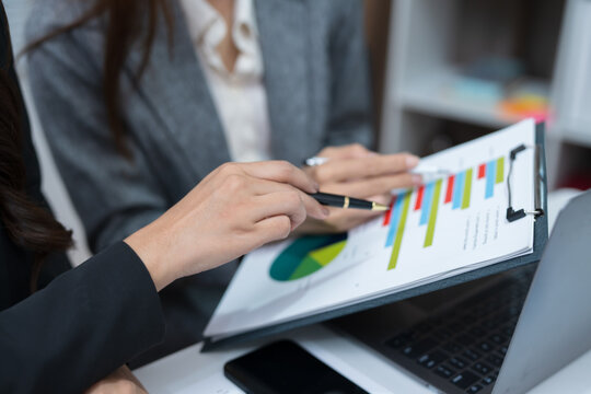  Two professional women work together at a desk, reviewing information on a laptop, collaborating on teamwork and business planning, and analyzing data.