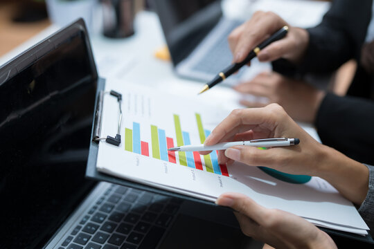  Two professional women work together at a desk, reviewing information on a laptop, collaborating on teamwork and business planning, and analyzing data.
