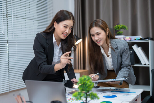  Two professional women work together at a desk, reviewing information on a laptop, collaborating on teamwork and business planning, and analyzing data.
