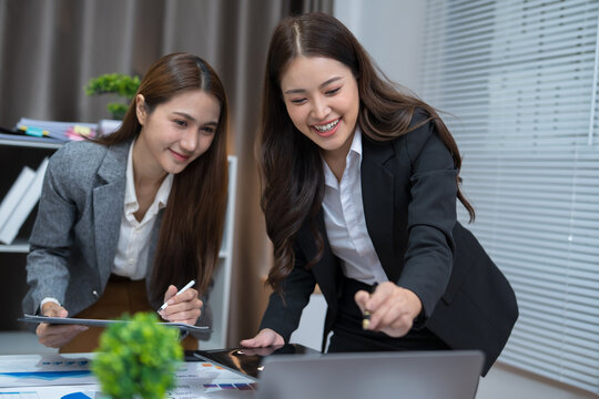  Two professional women work together at a desk, reviewing information on a laptop, collaborating on teamwork and business planning, and analyzing data.