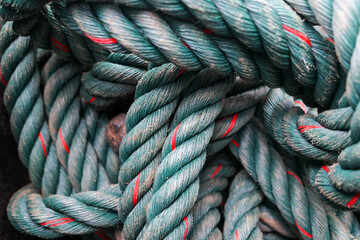 Thick teal rope coil with red tracer and weathered texture, closeup showing braided fibers and maritime wear conveying rugged utility and tactile detail © CoreRock