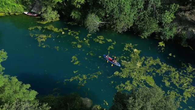 A couple in love canoeing and paddle boarding on a river with green water, algae, and water lilies; drone view of canoeing and kayaking in the Nera River gorges &ndash; Terni, Narni , Umbria, Italy
