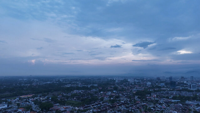 Panoramic aerial view of city skyline during blue hour with dramatic evening clouds.
