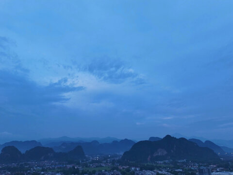 Blue evening sky above mountain landscape with dramatic clouds and natural scenery.
