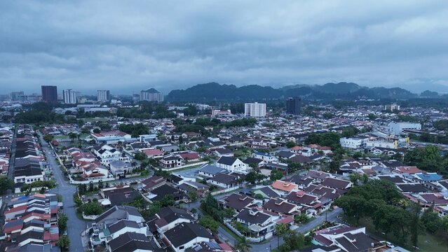 Residential neighborhood with urban skyline and mountain backdrop under cloudy sky.