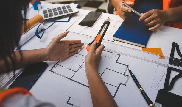 engineer and an architect reviewing blueprints and construction plans together at a bustling construction site