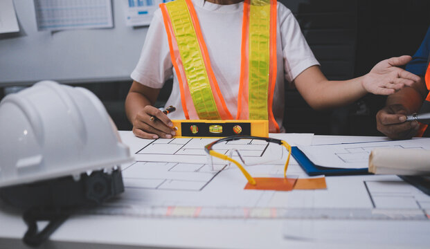 engineer and an architect reviewing blueprints and construction plans together at a bustling construction site