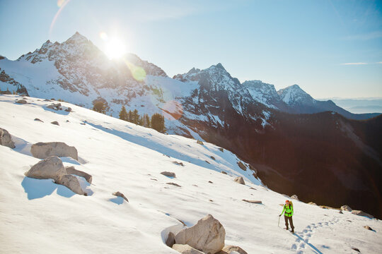 Backpacker climbing a snowy mountain on a sunny day