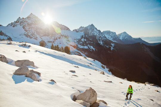 Hiker treks across sunny snowy mountains