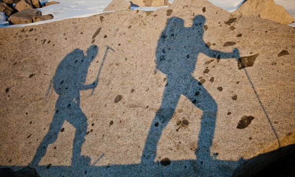 Two mountaineers cast shadows on a granite boulder