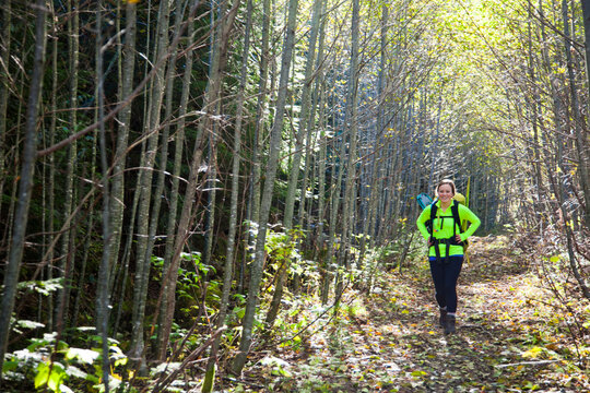 Smiling woman hikes on a sunlit forest path
