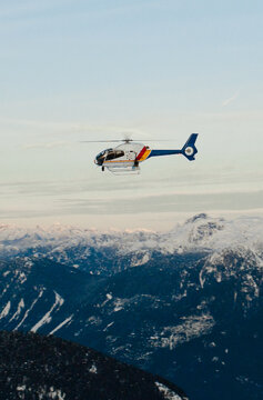 Police helicopter patrols above snowy mountain range