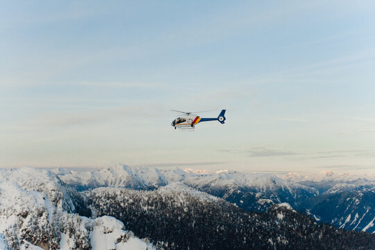 Police helicopter flying over a snowy mountain range