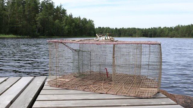 Net and box to catch fish at a lake. Fishing kit. Ready to use, at a wooden bridge. Summer day in July. Eken&auml;s, Finland.