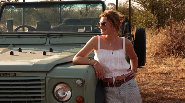 portrait of young woman and vintage safari vehicle, Zambezi National Park, Zimbabwe, Africa 