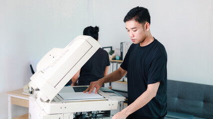 Obraz premium Young office worker operating a commercial photocopier in a modern workplace, representing document printing, copying, office technology, business services,